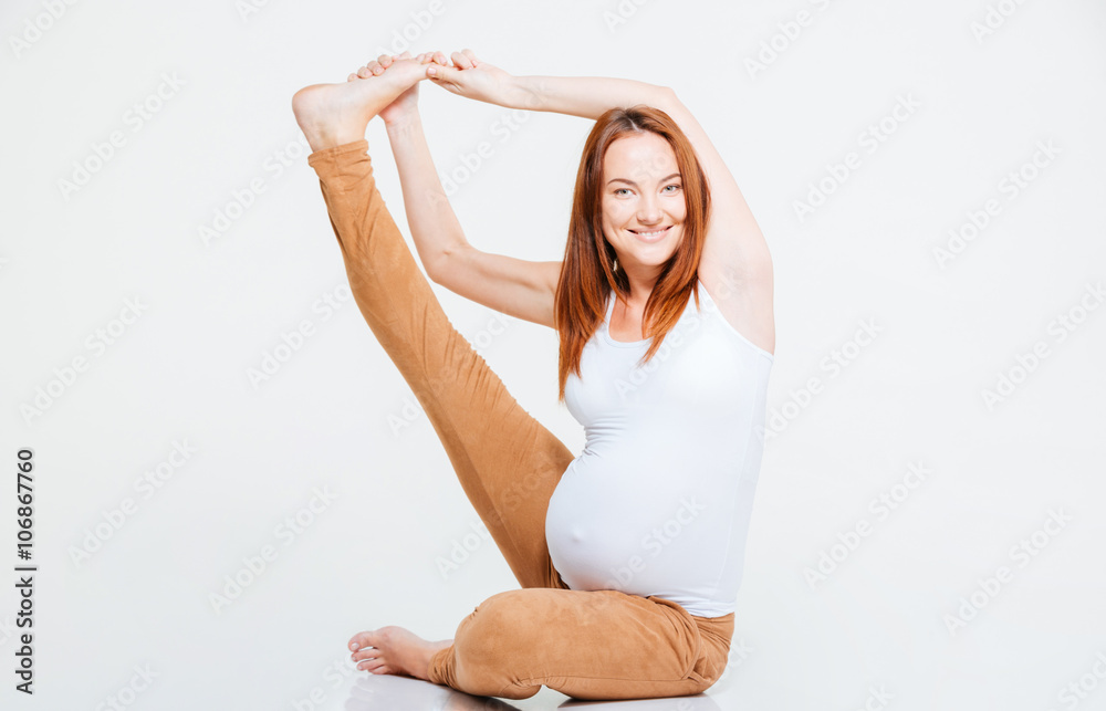 Happy pregnant woman stretching leg on the floor Happy pregnant woman stretching leg on the floor