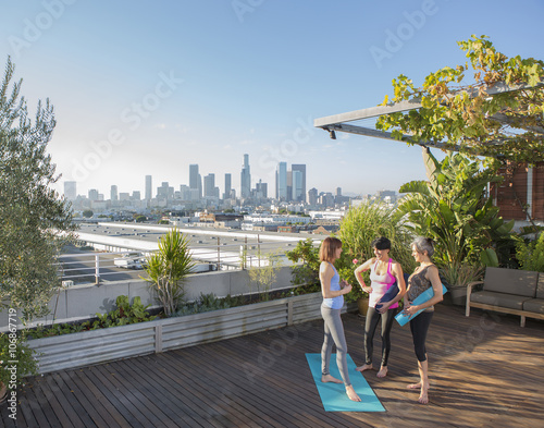 Women talking after practicing yoga on urban rooftop photo