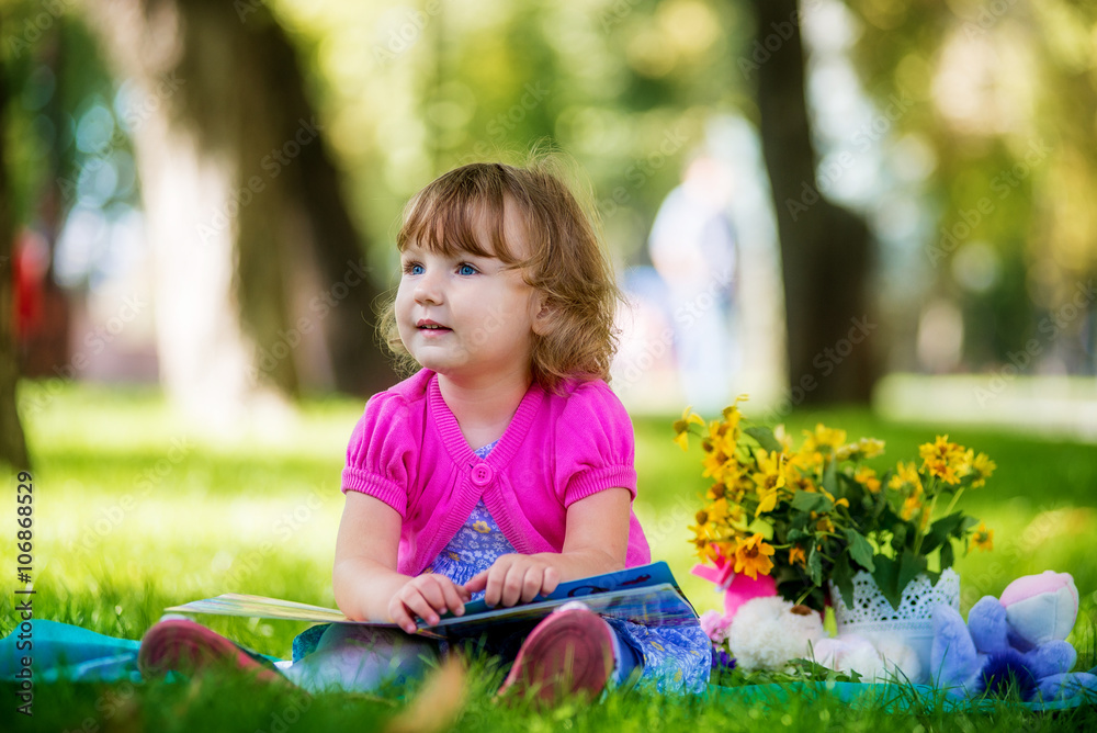 Little girl sitting in the park and reading a book Little girl sitting in the park and reading a book