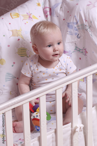 Little boy sitting in a crib