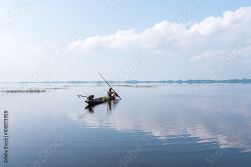 Fisherman on boat at wet land.