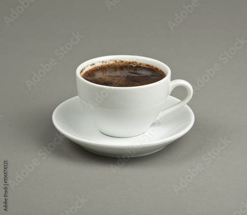 Cup of coffee and saucer on a gray background.