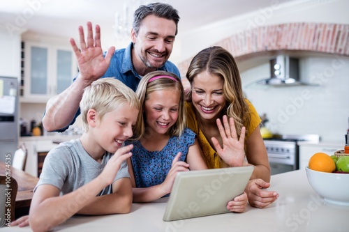 Parents and kids waving hands while using digital tablet for video