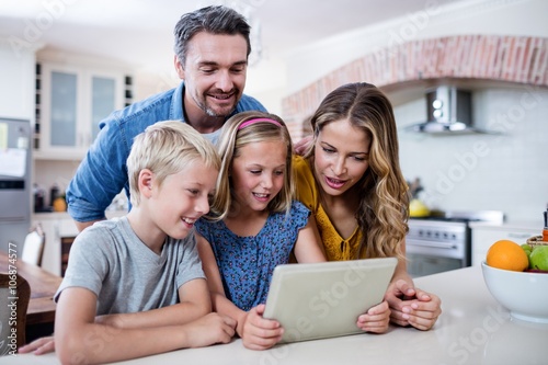 Parents and kids using digital tablet in kitchen