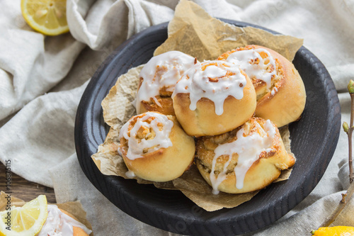 Cinnamon rolls with lemon glaze in wooden plate