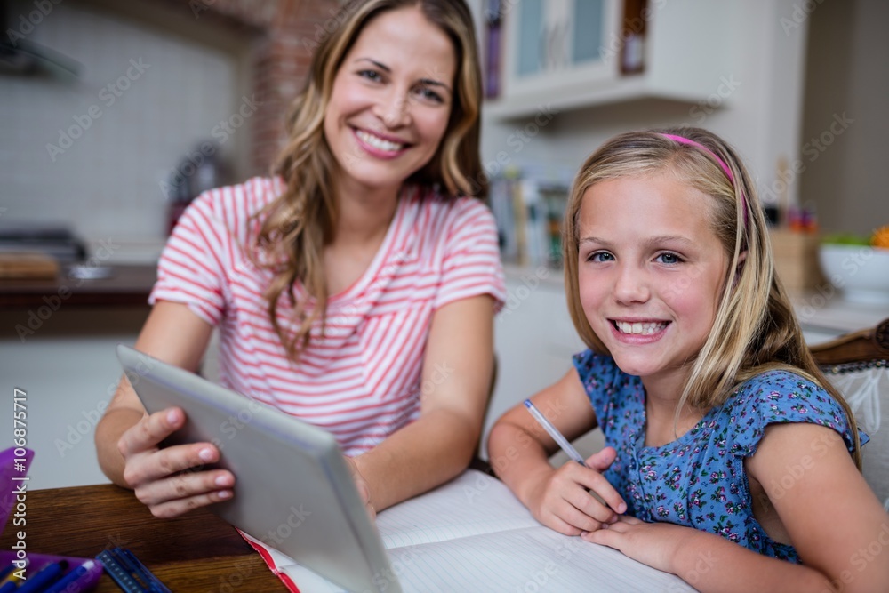 Mother using a digital tablet while helping her daughter Mother using a digital tablet while helping her daughter