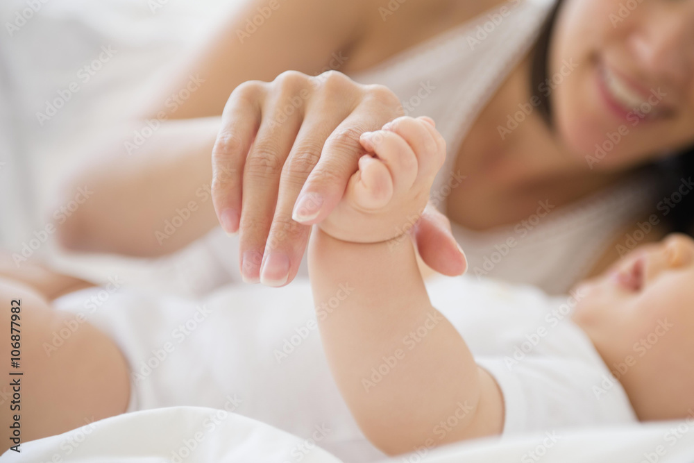 Mixed race mother playing with baby on bed Mixed race mother playing with baby on bed