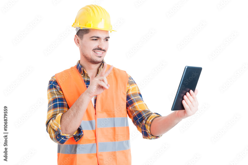 Smiling constructor using tablet and showing peace or victory ge Smiling constructor using tablet and showing peace or victory ge