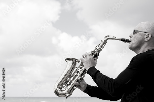 Canvas Print Saxophonist playing on saxophone on blue sky background