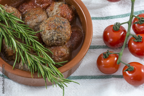 Meatballs with tomato sauce, cherry and rosemary on the white kitchen towel