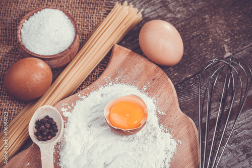 Pasta spaghetti with flour, egg on old wooden background