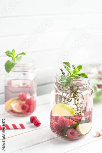 Summer refreshment drink. Water with cucumber, lime, ice and mint on rustic background. Pink Detox.