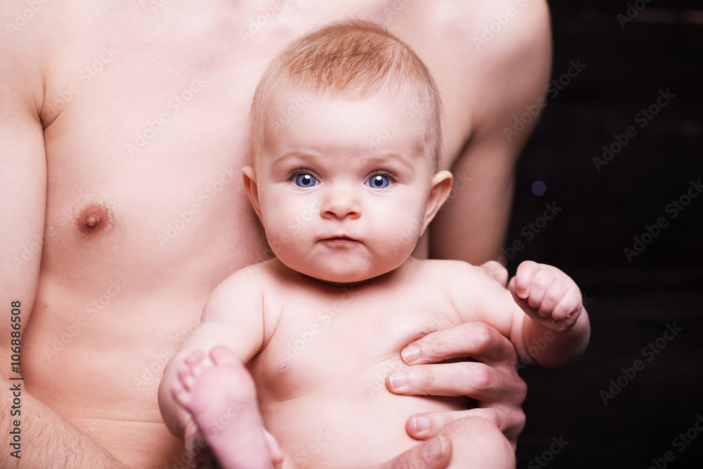 Young father is feeding his baby daughter.baby girl smiling at the hands of the father Young father is feeding his baby daughter.baby girl smiling at the hands of the father