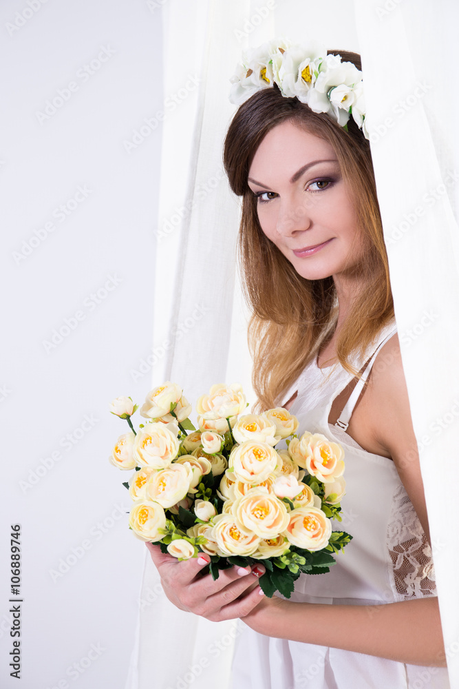 beautiful bride in white dress with flowers standing near the wi beautiful bride in white dress with flowers standing near the wi