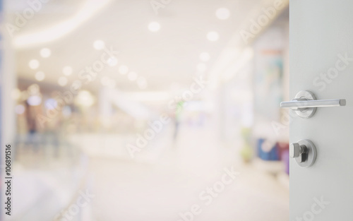 opened white door to shopping mall interior with bokeh as background