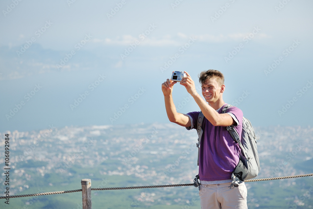 Obraz premium young hiker with backpack making himself photo on the top of the mountain Vesuvius, Italy
