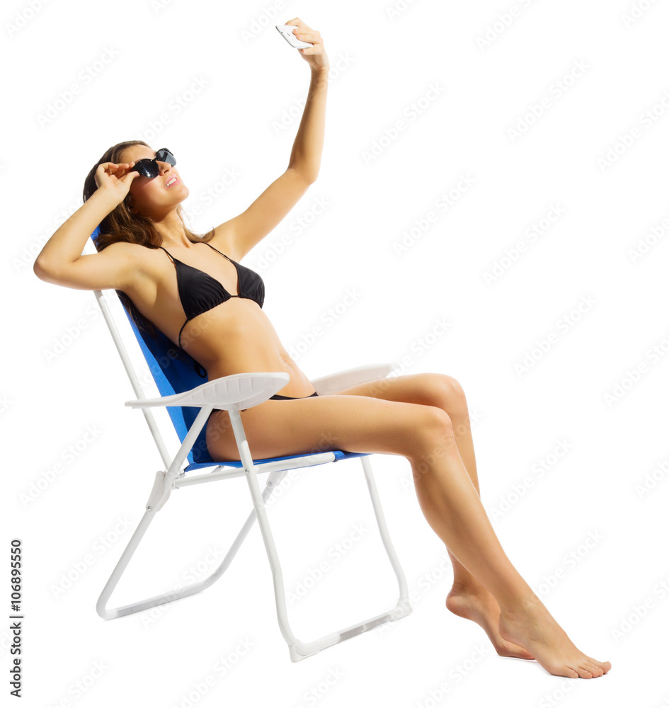 Young girl in swimsuite on chair with mobile phone