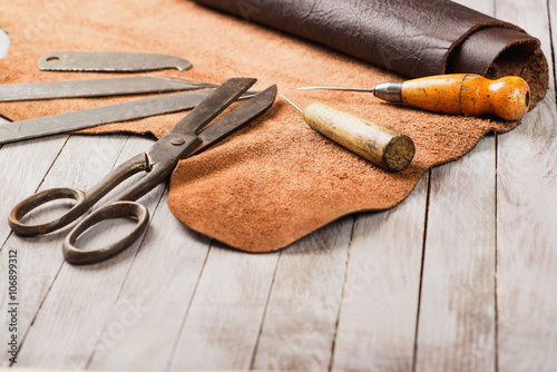 Leathersmith's work desk . Pieces of hide and leather working tools on a work table. photo