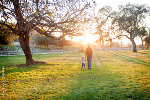 Father walking with son and daughter in sunlit field