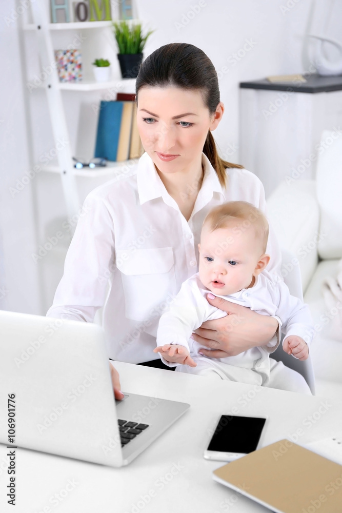 Businesswoman with baby boy working from home using laptop