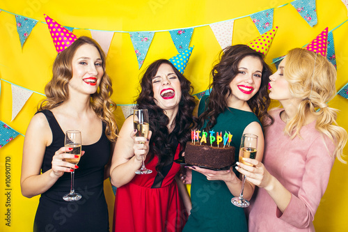 Portrait of joyful friends toasting and looking at camera at birthday party. Attractive friends celebrating a birthday. Smiling girls with glasses of champagne