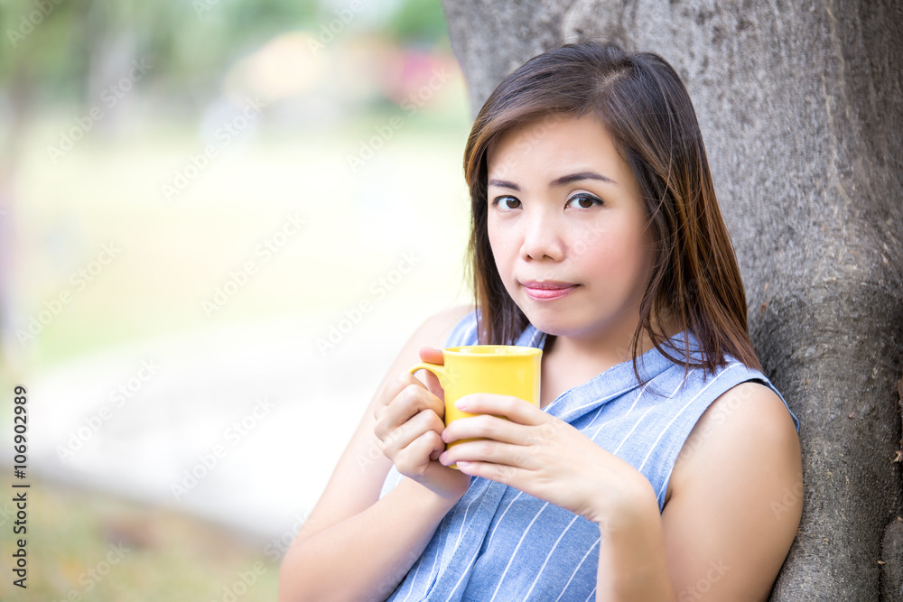 young women wear light blue shirt holding a yellow mug of coffe, young women wear light blue shirt holding a yellow mug of coffe,