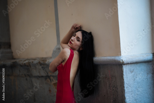 Portrait of a beautiful woman in a red dress with a bare back.