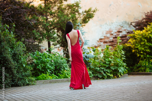 The young beautiful stylish girl with long blond hair, standing outdoors in a red dress at the event. Close up portrait of a beautiful sunset light © ostap_davydiak