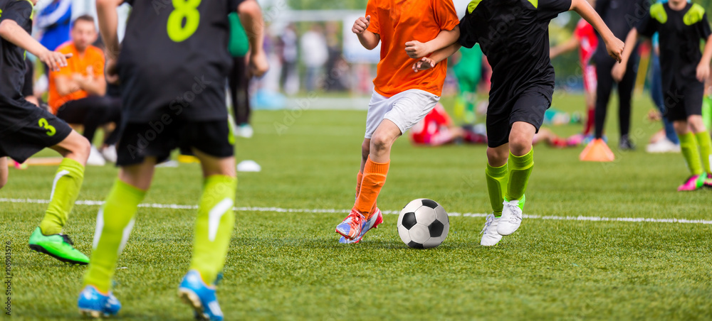 Obraz premium Young boys children in uniforms playing youth soccer football game tournament. Horizontal sport background.