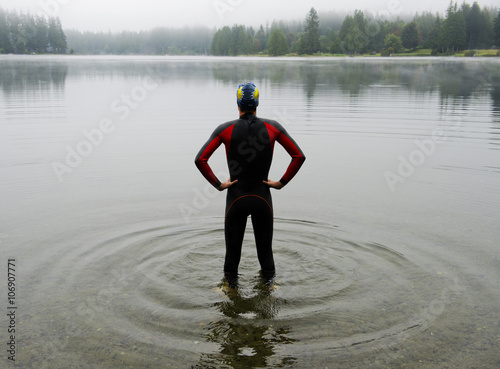 Young man in wet suit preparing to swim lake