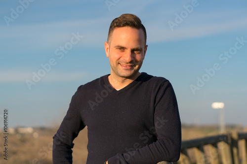 Glad man leaning on wooden fence in countryside