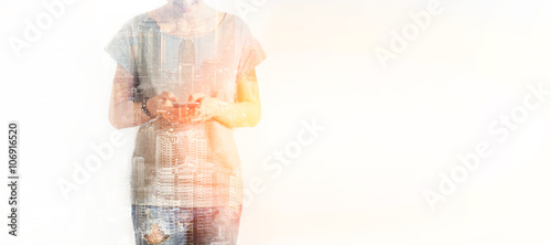 Closeup photo of stylish teenager girl wearing blank t-shirt and looking cell phone. Double exposure, panoramic view contemporary megalopolis background. Space for your business message.