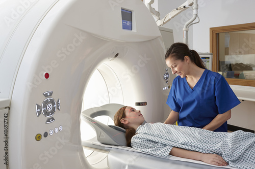 Radiographer reassuring girl going into CT scanner