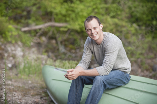 Portrait of young man sitting on upturned boat photo