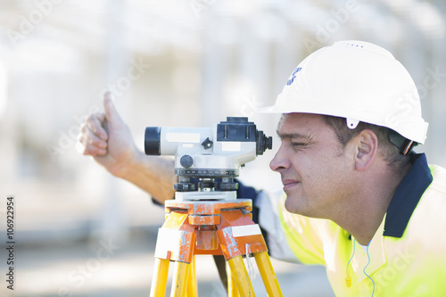 Surveyor looking through level on construction site