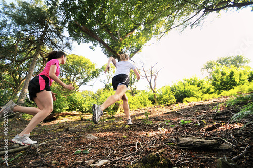 Two young women runners running up forest track photo