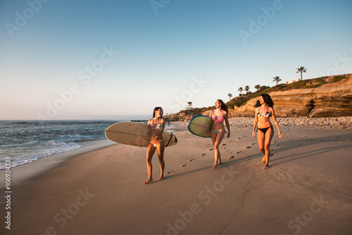 Surfers carrying surf boards, walking along beach
