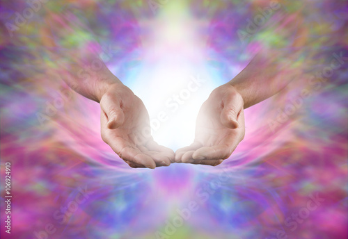 Sending Sacred Healing Energy - Male hands in open gesture with burst of white light between on a beautiful ethereal multicolored energy formation background with plenty of copy space