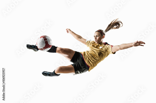 Studio shot of young female soccer player kicking ball mid air photo