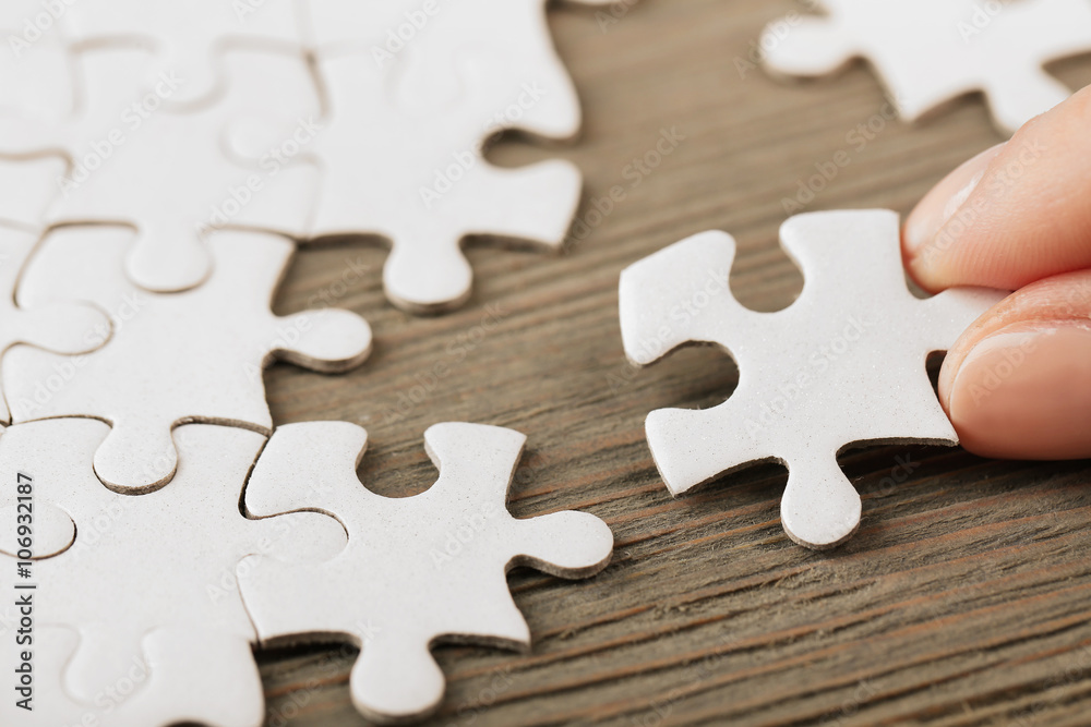 Woman playing with jigsaw puzzle on wooden table Woman playing with jigsaw puzzle on wooden table