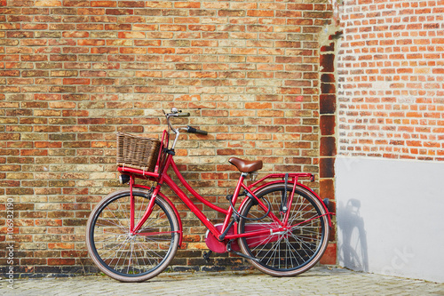 Red bicycle against brick wall in Brugge