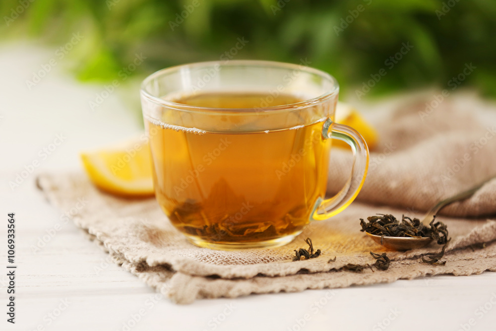 Glass cup of green tea with sliced lemon on wooden table with sackcloth closeup Glass cup of green tea with sliced lemon on wooden table with sackcloth closeup