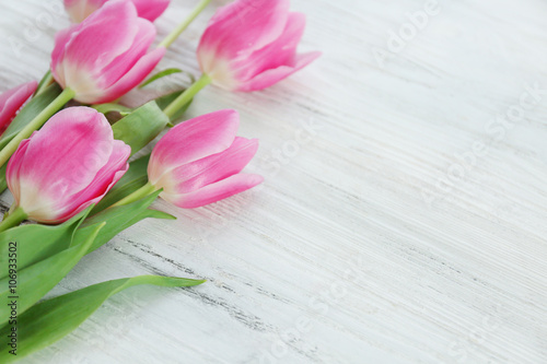 Fresh pink tulips on a wooden table, close up