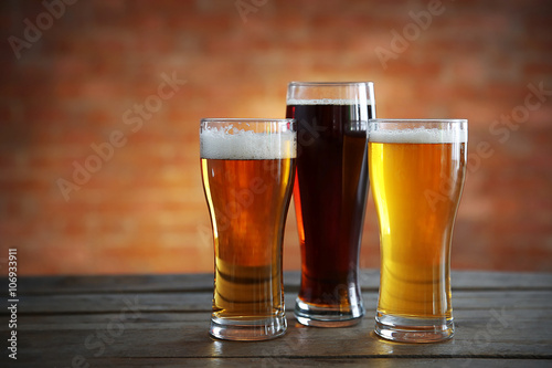 Glasses with different sorts of craft beer on brick wall background