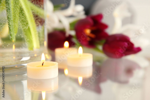 A bouquet of violet tulips and candles on a glass table, close up