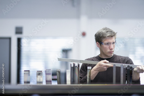 Mid adult male technician checking quality of products in engineering plant photo