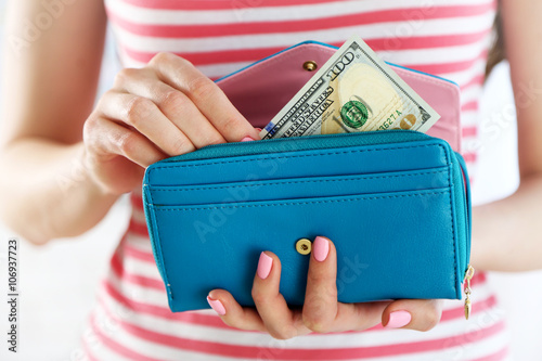 Young woman getting dollar banknote from purse