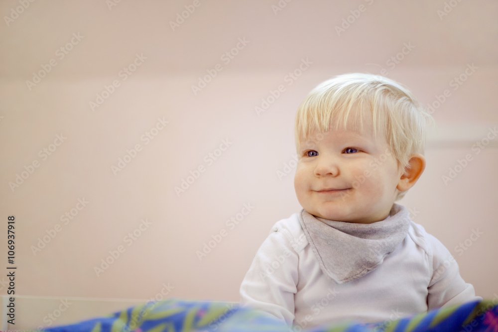 Portrait of cute fourteen month old baby boy sitting on duvet Portrait of cute fourteen month old baby boy sitting on duvet
