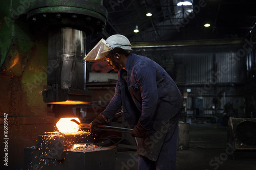 Forge worker pre forms steel billet on 5 tonne clear space hammer before it will be presented to set of two dies to be fully forged in hammer