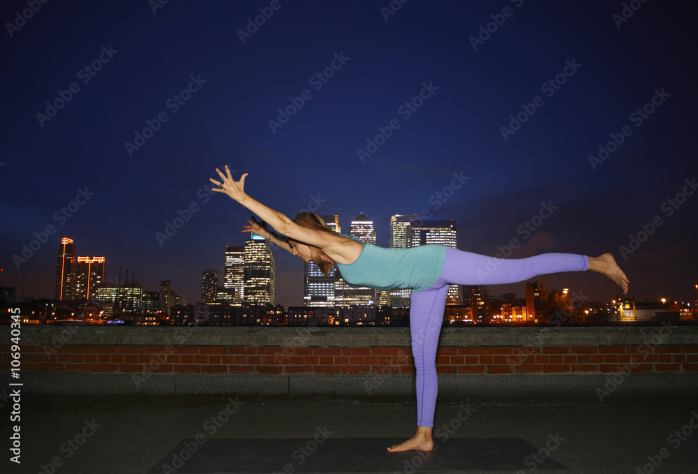 Mid adult woman practicing yoga on city rooftop Mid adult woman practicing yoga on city rooftop